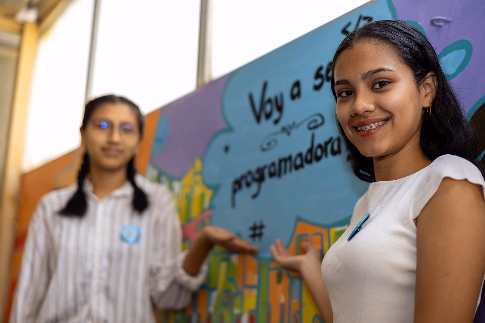 Dos estudiantes presentan un mural que dice 'Voy a ser programadora'